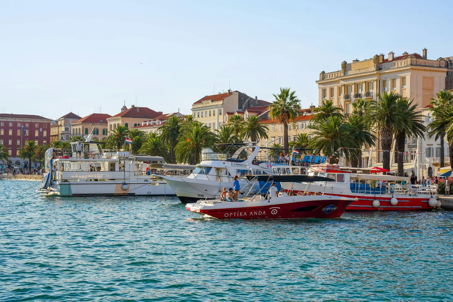 Boats moored along the Riva in Split, with palms and the waterfront behind